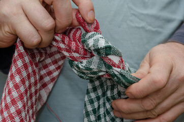 Two men's hands tie two towels together.