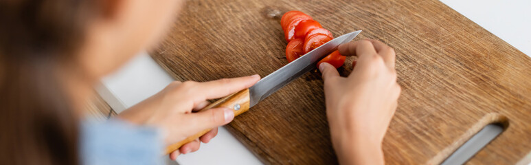 Cropped view of kid cutting cherry tomato in kitchen banner