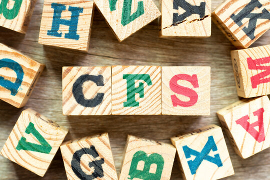 Alphabet letter block in word CFS (Abbreviation of Container Freight Station, Certified fund specialist or Chronic fatigue syndrome) with another on wood background