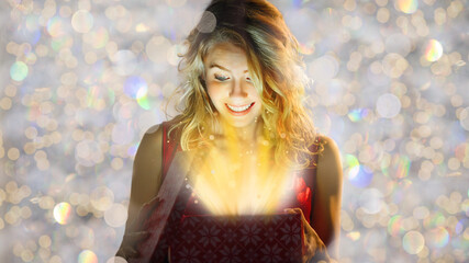 Smiling and happy blond woman with christmas gift box on the golden, light background. Shopping...