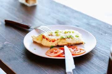 Lunch on the table: chicken steak with tomatoes with fork and knife