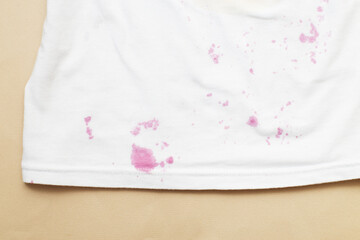 dirty stains on a white T-shirt from berries and drink on beige background