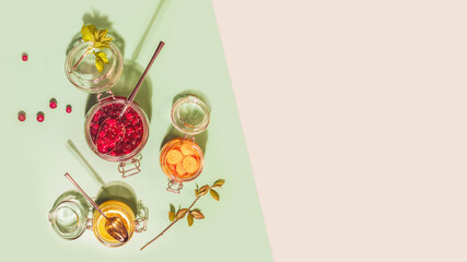 Fermentation of fruits vegetables and berries. Food banner with glass jars with fermented honey cranberries, lemon and carrot on mint and pink background with copy space. Homemade remedy for immunity