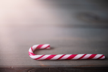 Candy cane in the sunshine on wooden background.
