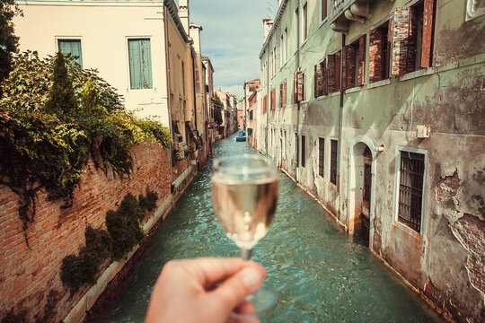 Drinking white wine over water canals in Venice. Bar visitor walking through ancient streets of famous italian city