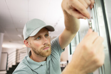 young handyman in uniform changing door lock