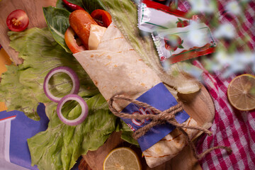 Fresh sausage roll with fresh tomatos, salad, cheese and onions isolated on bright blue background. top view.cope space.selective focus