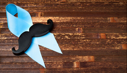 Prostatitis symbol. Mustache on a blue ribbon on a wooden background with place for text.