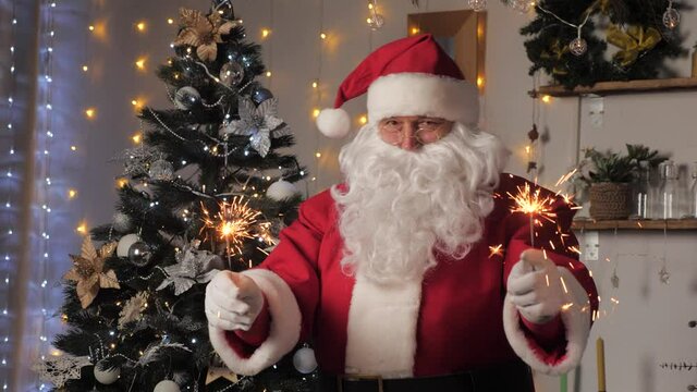 Happy, magical, children's, family holiday, Christmas. Happy Santa Claus is dancing with sparklers, enjoying music. Santa claus is having fun in room with Christmas tree. New Year, Christmas