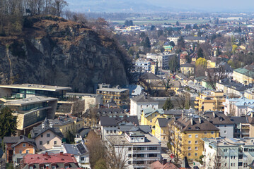 Austria. Spring. Day. Salzburg. View of a vertical mountain wall with a forest at the top and residential buildings below. 