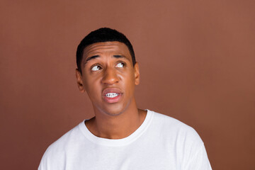 Photo of unsure millennial brunet guy look promo wear white t-shirt isolated on brown color...