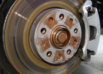 The front disc brake is a close-up on a car in the process of replacing a new tire. The rim is...