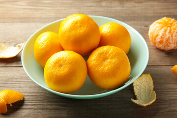 Fresh mandarin oranges fruit on mint bowl on grey wooden background.