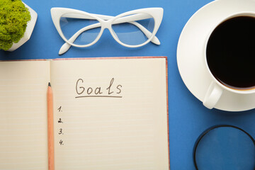 My Goals as memo on notebook with cup of coffee on blue background.