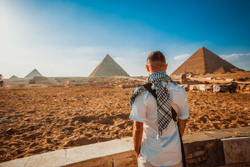 A tourist man stands with his back to the camera and looks at the pyramids. Meditation near the pyramids in Cairo, Egypt
