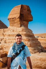 A young man of tourists takes pictures in front of the pyramids and the Sphinx of Giza in Cairo,...