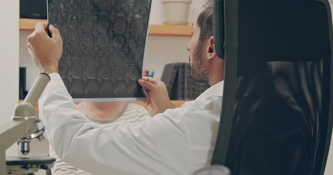 Family Medical Doctor Showing Brain Test Results to a Senior Patient in a Health Clinic. Prevention and scanning of human internal organs.