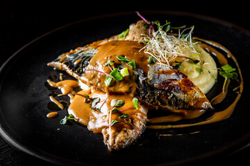Fillet of mackerel with mashed potatoes and celery on dark background