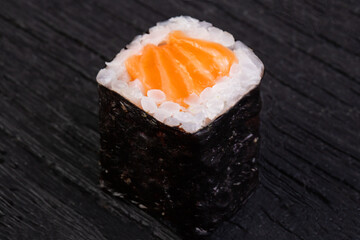 Roll of salmon on a wooden black