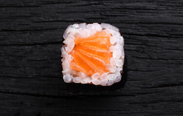 Roll of salmon on a wooden black