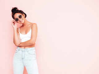 Young beautiful smiling female in trendy summer clothes. Sexy carefree woman posing near pink wall in studio. Positive brunette model having fun and going crazy. Cheerful and happy