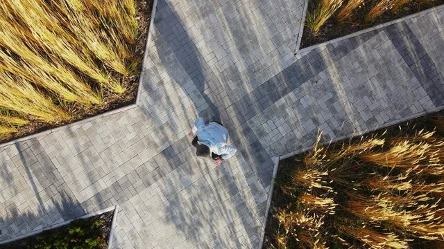 A middle-aged man dancing braidance on the street. Aerial photography of footwork in the middle of street tiles and vegetation