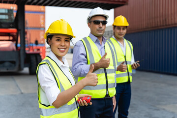 woman worker working with Foreman, standing with ware a yellow helmet to control loading and check a quality of containers from Cargo freight ship for import and export at shipyard or harbor