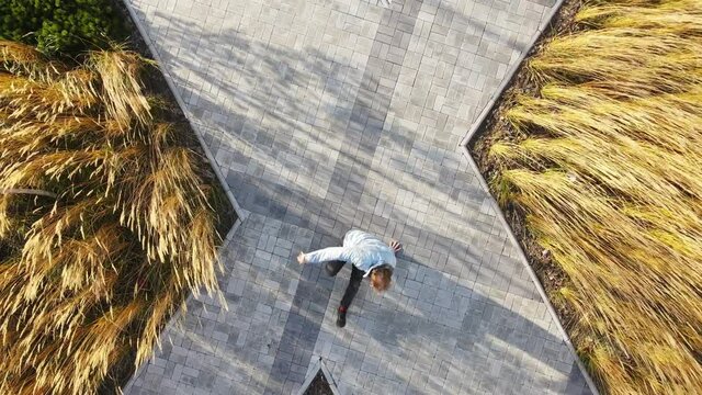The dancer makes a breakdancing move on one hand. Dancing on the street. Gray tiles on the background of the dancer. Aerial photography on freeze in breakdance.
