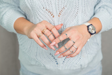 Women's hands with a beautiful manicure and rings are folded on the chest
