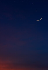 Obraz na płótnie Canvas Crescent moon on dark blue twilight sky vertical symbol of Islamic religion and well editing text Arabic Ramadan, Eid al Adha, Eid al Fitr, Muharram on free space