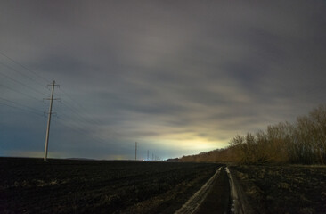 Obraz premium railroad tracks in the morning forest in the night . Night landscape. Nightsky and clouds . Stars in the sky . Lights of the city . Evening forest . Landscapes of Ukraine . Night and morning time 