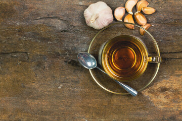 Garlic tea in transparent glass with garlic on rustic wooden background.