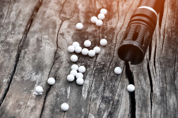 Closeup of white plastic bullets of airsoft gun or bb gun on wooden floor, soft and selective focus...