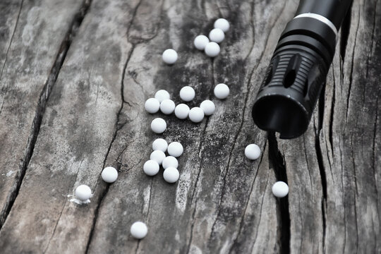 Closeup of white plastic bullets of airsoft gun or bb gun on wooden floor, soft and selective focus on white bullets.