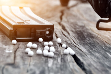 Closeup of white plastic bullets of airsoft gun or bb gun on wooden floor, soft and selective focus on white bullets. - obrazy, fototapety, plakaty