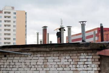 There are many chimneys on the roof of a residential building.