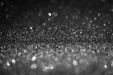 Black glitter lights. Shiny sparkles, bokeh effects, glowing surface. Selective focus, christmas abstract background