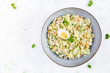 Festive salad with ham, cucumber, boiled eggs, sweet corn and mayonnaise on rustic. Top view, above