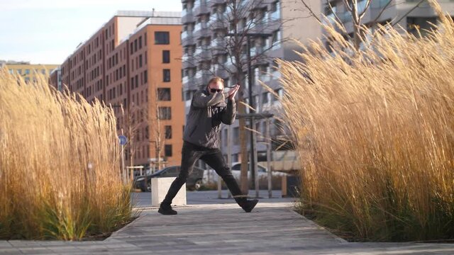 A man in dark glasses goes to the camera and dances a dance.