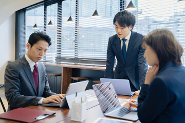 ノートパソコンで会議をする３人の男女のビジネスマン