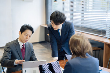 ノートパソコンで会議をする３人の男女のビジネスマン