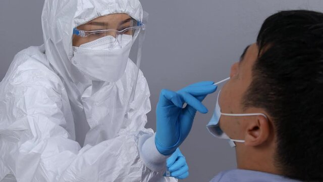 doctor with PPE suit test coronavirus(covid-19) to young man by nasal swab