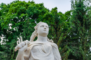 An ancient sculpture of a woman made of marble in the park.