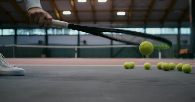 Lots of tennis balls lie on the rubberized floor of the indoor tennis court