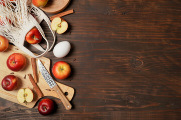 Apple baking seasonal concept. Ingredients for apple pie (red apple, flour, eggs, sugar, cinnamon) on a rustic wooden table. Top view flat lay. Free space for your text.