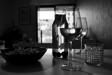 table setting, dinner, two glasses of wine, white wine, carafe, the shape of glasses, glass with water, blackberries, a bowl of salad, serving the dinner, table surface, window, blurred background 