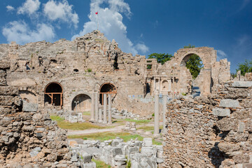 Outside view of Side ancient theater, agora and colonnaded square. Cloudy blue sky. Selective Focus columns and ruins.