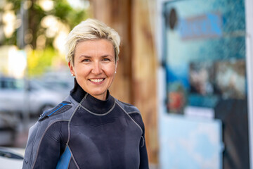 Portrait of a happy scuba diver woman in a wet suit. - obrazy, fototapety, plakaty