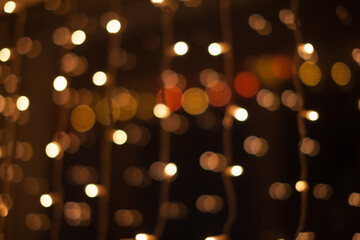 Abstract bokeh lights. Defocused shining yellow light leaks on dark background. New year, christmas garlands flecks.