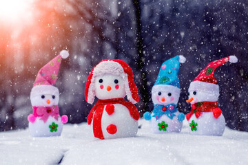 Toy snowmen in the forest during a snowfall. Christmas and New Year greeting card